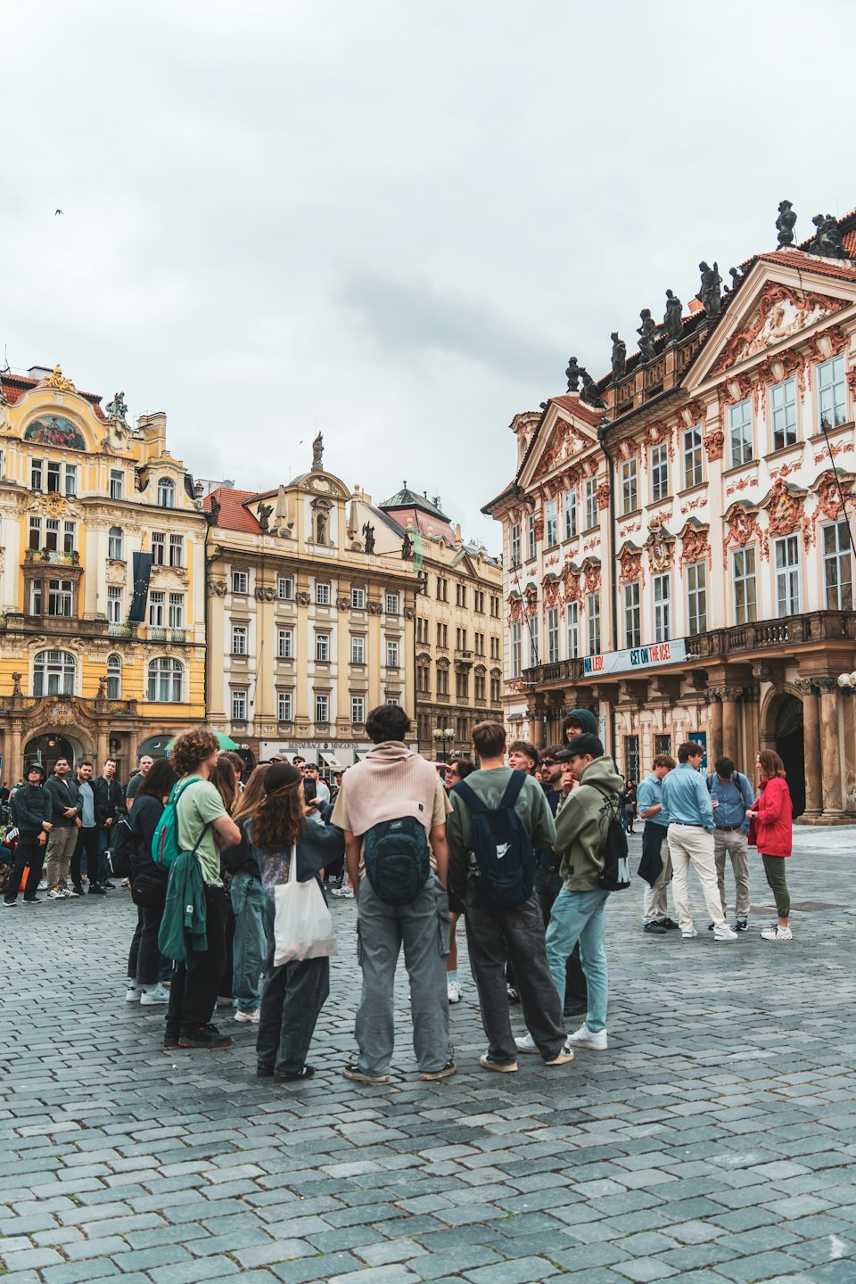 A group of tourists stands in a historic European square.
