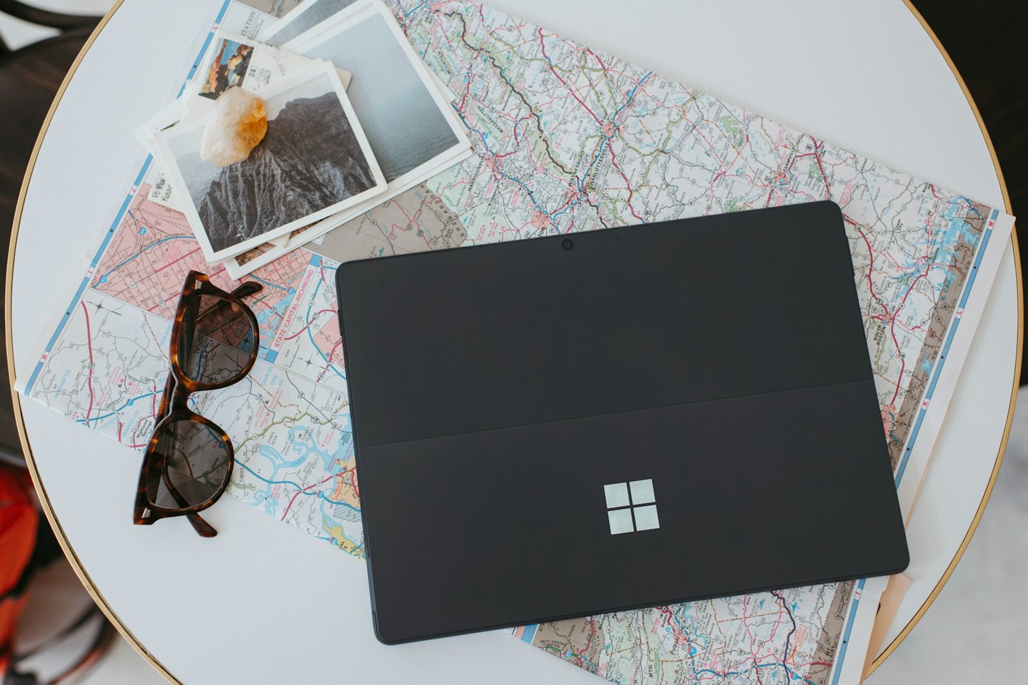 Laptop and travel items laid out on a map for planning a trip.