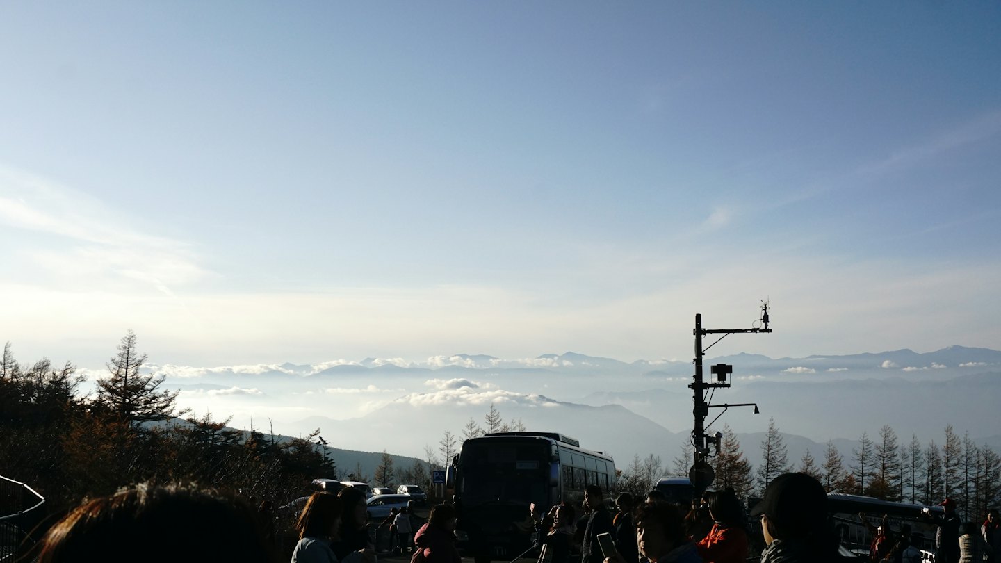 Tour bus and people at mountain viewpoint.